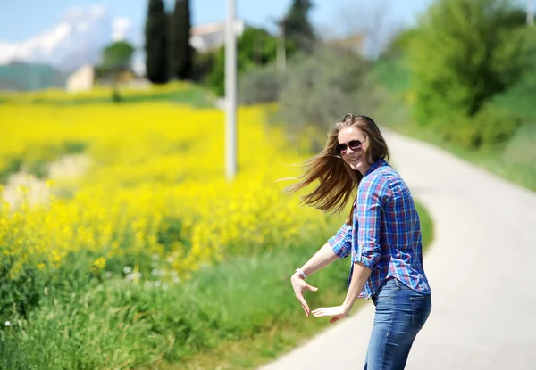 La chica va en el camino entre flores amarillas — Foto de Stock