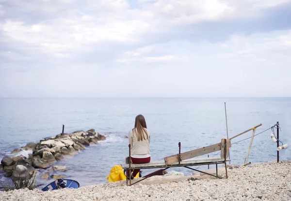 La chica sola se sienta en la orilla del mar — Foto de Stock