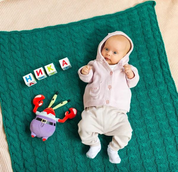 O bebê em fraldas está em uma cobertura entre brinquedos — Fotografia de Stock