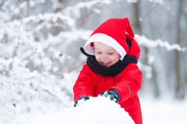 Çocuk kar kardan adam oluşturur.