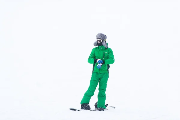 The athlete snowboarder in green overalls Stock Photo
