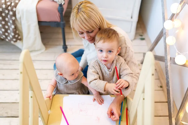 Madre entrena a los niños pequeños para escribir y dibujar . —  Fotos de Stock