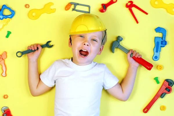 Lindo niño rodeado de herramientas de juguete vista superior. Niño feliz jugando con un conjunto de herramientas de juguete. Concepto de educación infantil Fotos De Stock Sin Royalties Gratis