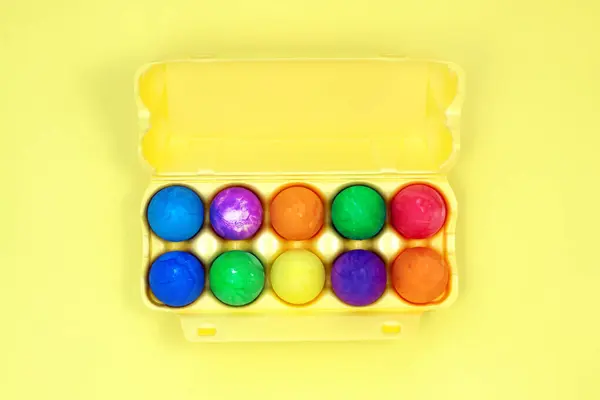 Zece ouă multicolore de Paște în cutie de ouă galbene pe fundal galben spațiu de copiere — Fotografie, imagine de stoc
