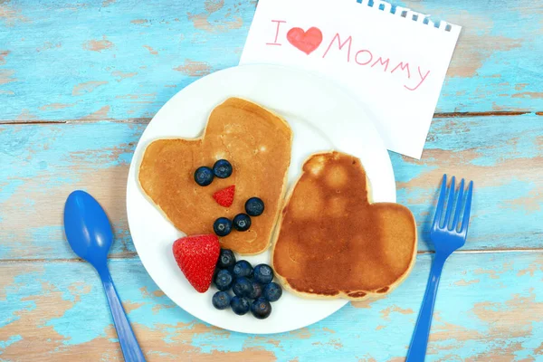 Hjärtformade pannkakor med blåbär och jordgubbar. Frukost för mamma på mödradagen. Stockbild