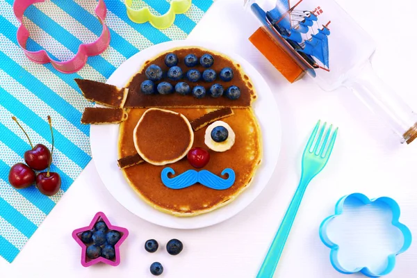 Rolig mat för barn. Söta piratpannkakor med blåbär. Kreativ idé för barn frukost. Stockbild