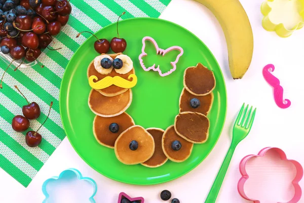 Larv eller maskformade pannkakor med bär på grön tallrik, ovanifrån. Hälsosam mat för barn. Rolig mat för barn. Royaltyfria Stockfoton