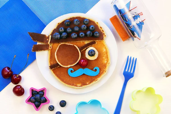 Söta piratpannkakor med blåbär. Kreativ idé för barn frukost. Stockbild