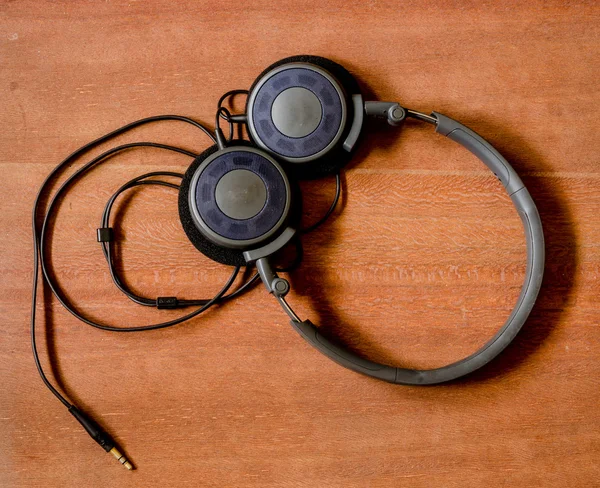 Auriculares negros en el tablero de madera viejo —  Fotos de Stock