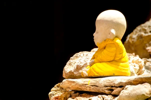 Pequena estátua de buddha na rocha e fundo preto — Fotografia de Stock