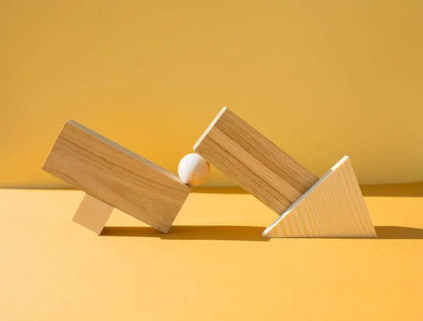 Geometrical figures composition. Wooden objects on yellow background. Balance, art and design concept.