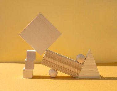 Sarı arka planda dengeli ahşap figürler. Denge ve tasarım kavramı.