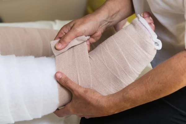 Donna bendaggio gambe del paziente — Foto Stock
