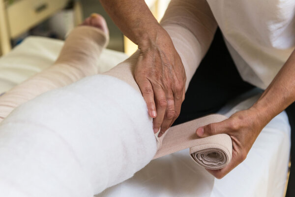 Женщина перевязывает ноги пациентке
