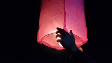 Gece karanlığında gökyüzü fenerini tutan insanların görüntüsü.