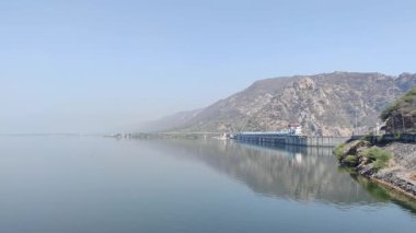 Gün ışığında mavi gökyüzü altında dağlık bir yerdeki baraj manzarasının görüntüsü.