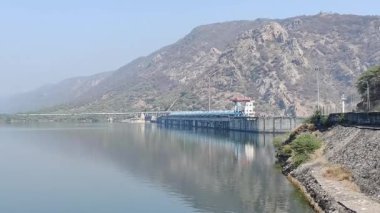 Gün ışığında mavi gökyüzü altında dağlık bir yerdeki baraj manzarasının görüntüsü.