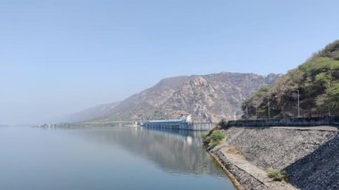 Gün ışığında mavi gökyüzü altında dağlık bir yerdeki baraj manzarasının görüntüsü.