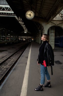 Tren istasyonunda saatine bakan deri ceketli güzel bir kadının portresi. St. Petersburg 'daki Vitebsk tren istasyonunu bekliyorum..