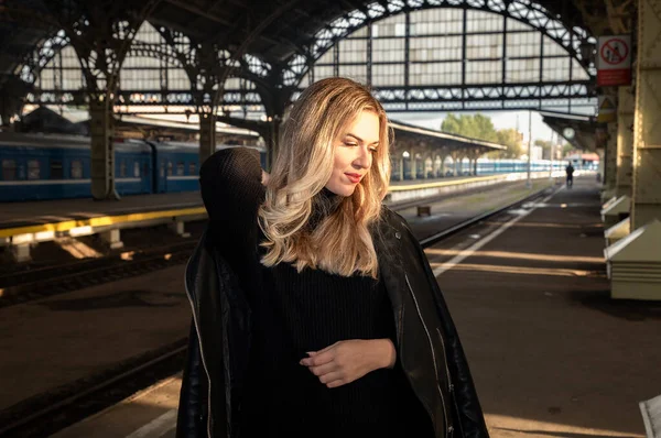 Tren istasyonunun peronunda deri ceketli genç güzel bir sarışının portresi. Tren istasyonunun platformunda deri ceketli güzel bir sarışın..