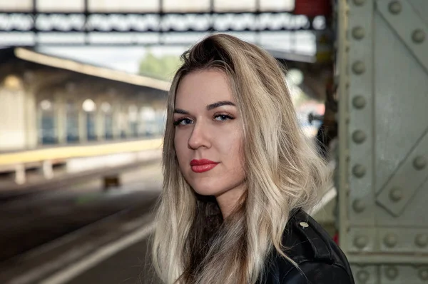 Tren istasyonunda deri ceketli güzel bir sarışının portresi..