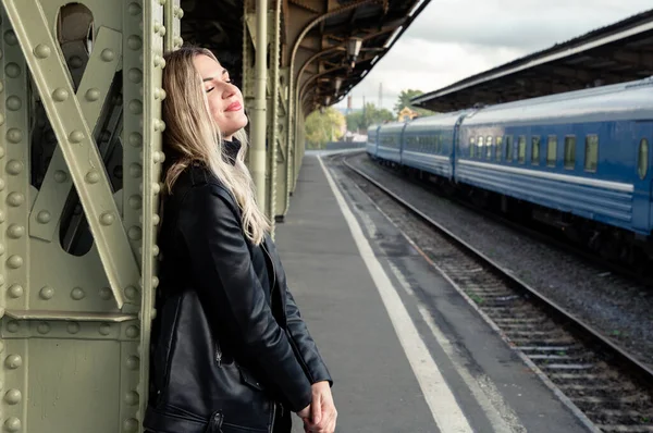 Tren istasyonunda deri ceketli güzel bir sarışının portresi..