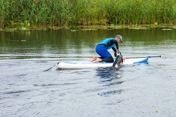 Suzdal, Rusya - 12 Ağustos 2020: Kürek tahtasında adam ve Kamenka nehrinde köpek