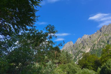 Kuzey Kafkasya 'nın güzel dağ zirveleri mavi bulutlu gökyüzünün arka planına karşı. Kuzey Osetya Cumhuriyeti - Alania
