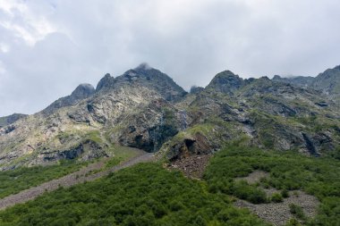 Kuzey Kafkasya 'nın güzel dağ zirveleri mavi bulutlu gökyüzünün arka planına karşı. Kuzey Osetya Cumhuriyeti - Alania