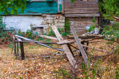 Çimlerle ve ağaçlarla çevrili terk edilmiş eski bir köy evi.