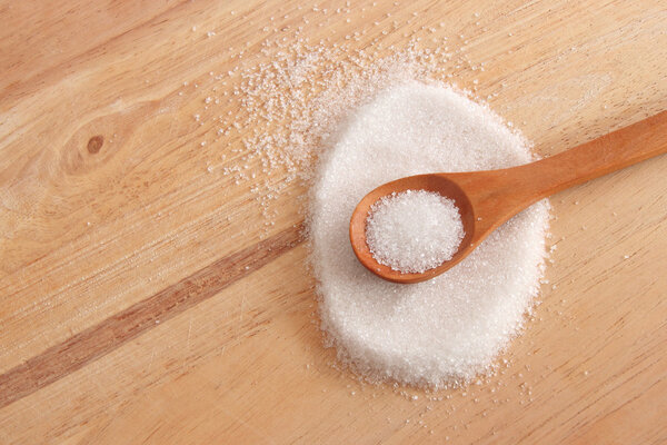 белый сахар в деревянной ложке
