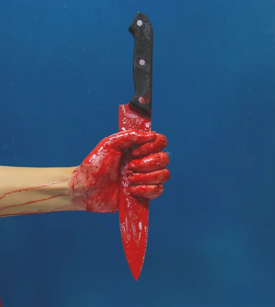Uma mão sangrenta segurando uma grande faca coberta de sangue — Fotografia de Stock