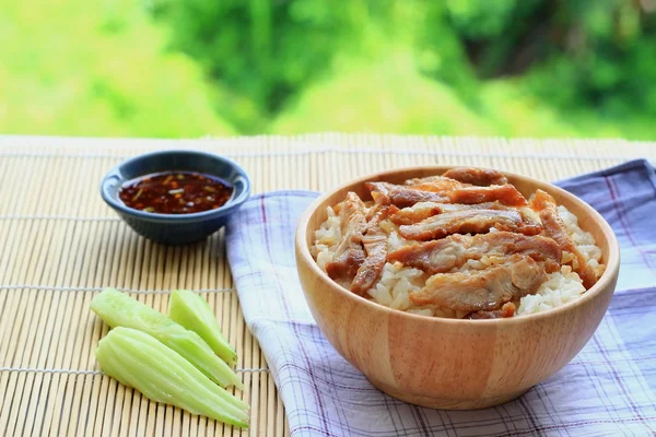 Roast pork with rice and tasty sauces and spices in a wooden bowl on a wooden floor — Stock Photo, Image