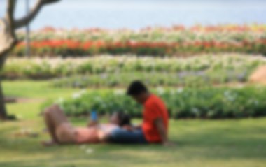 Şirin çift telefon bir parkta yalan sunu etki için arka plan bulanık