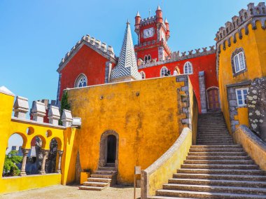 Renkli Pena Sarayı ya da Palacio da Pena Sintra Dağları 'ndaki bir tepenin üstünde duruyor, mavi gökyüzü arka planında. Çeşitli mimari stil ve renklere sahip ulusal anıtın dış görünüşü