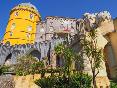 Renkli Pena Sarayı ya da Palacio da Pena Sintra Dağları 'ndaki bir tepenin üstünde duruyor, mavi gökyüzü arka planında. Çeşitli mimari stil ve renklere sahip ulusal anıtın dış görünüşü