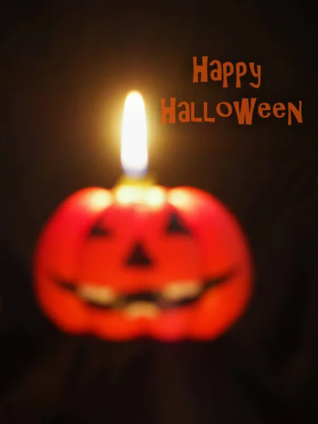 Cadılar Bayramın kutlu olsun, siyah arkaplanda mor mor bir yazı, balkabağı şeklinde, yanan mum. Gülen Cadılar Bayramı Jack, turuncu balkabağı. Tebrik kartı. Özellikle odak dışı, bulanık resim.