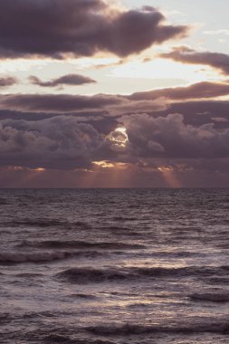 Güneş denizin üzerinden bulutların arasından doğuyor.