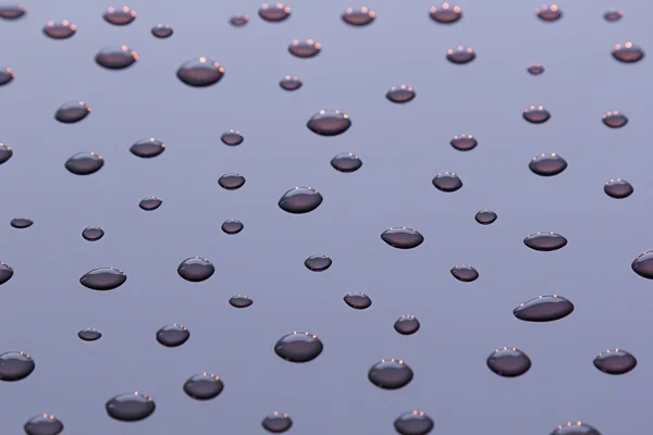 Las gotas de agua sobre un fondo lila . — Foto de Stock