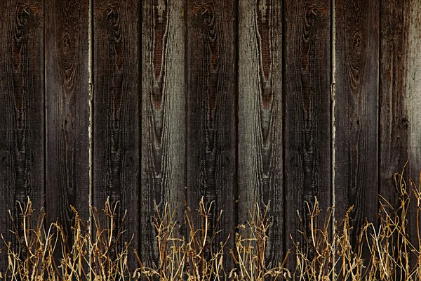 Старый деревянный забор. Винтажные доски и сухая трава. Деревянный фон. Деревянная текстура . — стоковое фото