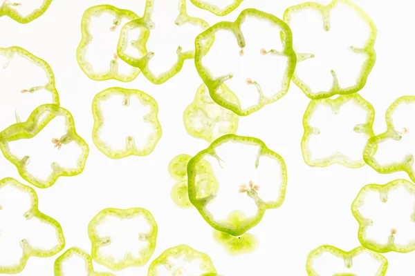 Gesneden verse groene en rode peper ringen op een witte achtergrond. Decoratief patroon. Voedsel achtergrond. Concept art. — Stockfoto