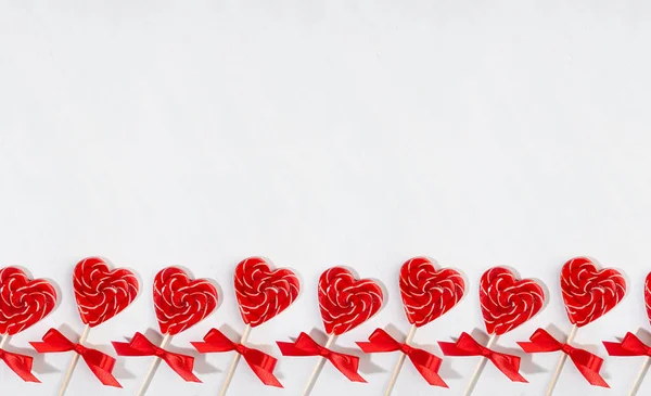明亮的情人节背景 甜甜的红色棒棒糖心在白色木板上如无缝边界 横幅布局 — 图库照片