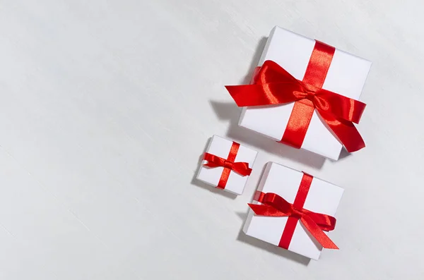 节庆背景 白色礼品盒 红色丝带 阳光下 白色木板上有阴影 顶视图 — 图库照片