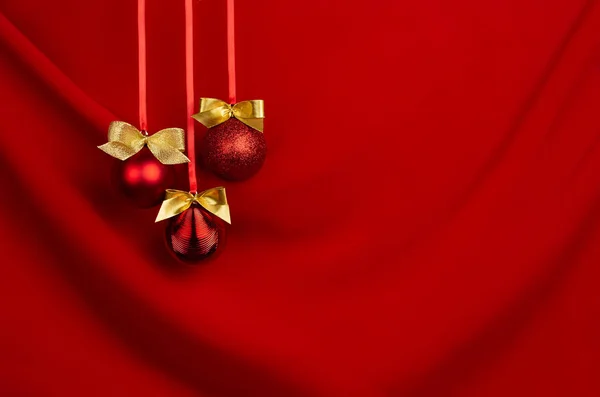 丰富的红色圣诞背景 闪烁着金色蝴蝶结的球挂在缎带上 呈饱和丝状波浪状背景 复制空间 招贴画 小册子设计的新年背景 — 图库照片