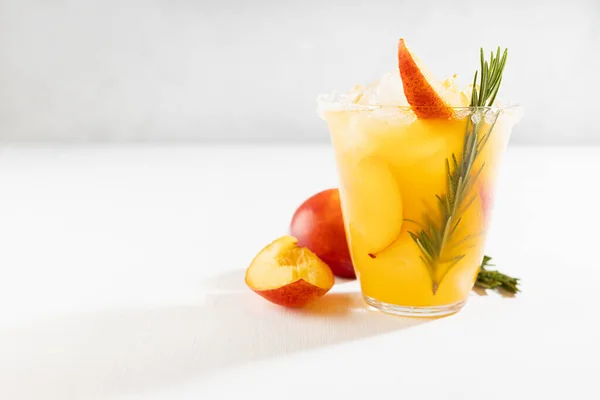 自制有机冷蜜桃汁 绿色迷迭香枝条 湿玻璃杯中的水果片 配料在雅致的现代白色厨房内部 — 图库照片