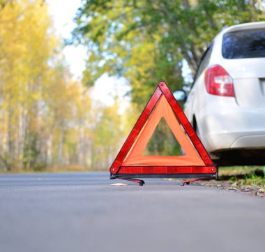 Beyaz bir araba ve ormanın arka planında dur işareti var. Yol yardımı kavramı, seyahat hadiseleri, araba tamiri. Boşluğu kopyala