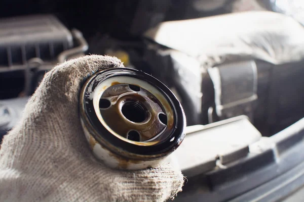 changing engine oil for a car, a man in a glove holds an old oil filter. concept car maintenance and repair. copy space.