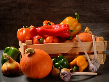 Taze sebzelerle dolu ahşap bir kutu - dolmalık biber, soğan, sarımsak, balkabağı. Hasat konsepti, sağlıklı yiyecekler ve kimyasallar olmadan tarım. Boşluğu kopyala.