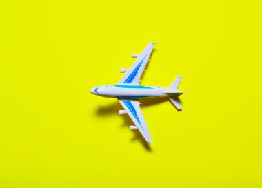 Oyuncak uçağı sarı arka planda uçurmak. İş gezisi konsepti, tatil uçuşu, sıcak bölgelerde tatil. Düz yat. Boşluğu kopyala.