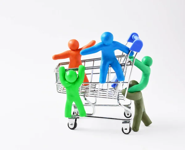 Plasztikumból készült figurák gurítanak egy bevásárlókocsit. koncepció kedvezmények, vásárlás ajándékok, felkészülés az ünnepre. másolás helye. — Stock Fotó